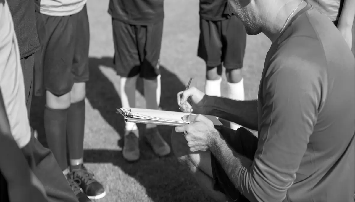 Un entrenador anota en su planilla junto a sus jugadores